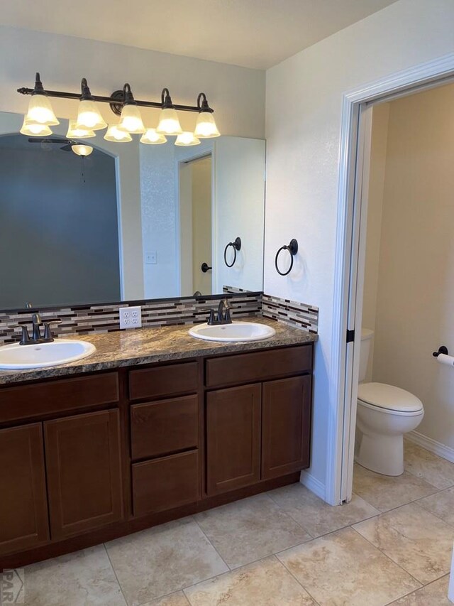 full bathroom featuring toilet, tile patterned flooring, double vanity, and a sink