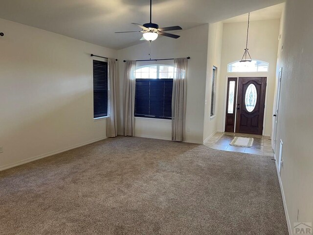 entrance foyer with baseboards, high vaulted ceiling, a ceiling fan, and light colored carpet