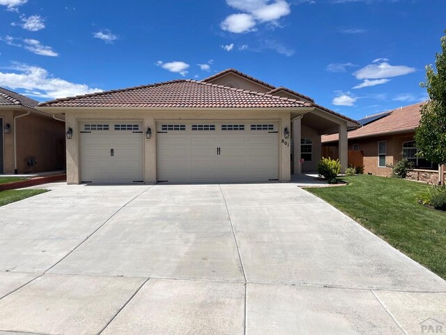 view of front of house with concrete driveway, a tile roof, an attached garage, and stucco siding