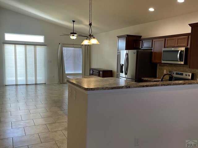 kitchen featuring lofted ceiling, hanging light fixtures, appliances with stainless steel finishes, backsplash, and dark countertops