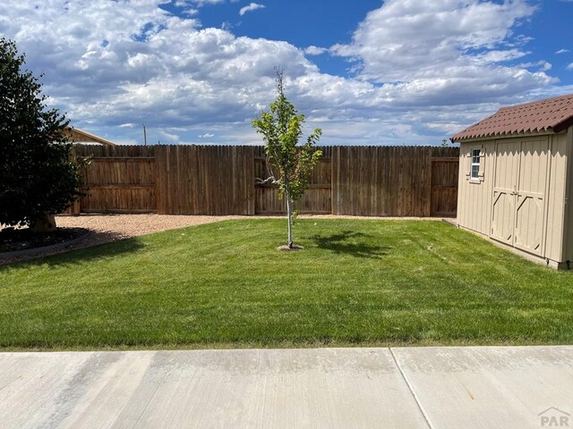 view of yard featuring a storage shed, an outdoor structure, and a fenced backyard