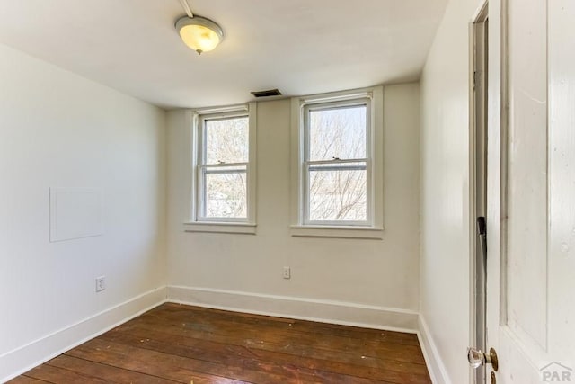 unfurnished room featuring baseboards, visible vents, and dark wood-style floors