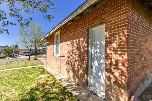 view of side of home featuring a yard and brick siding