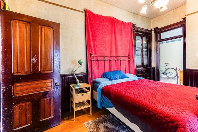 bedroom with wainscoting and wood finished floors