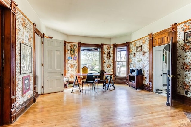 interior space featuring baseboards, wallpapered walls, and light wood-type flooring