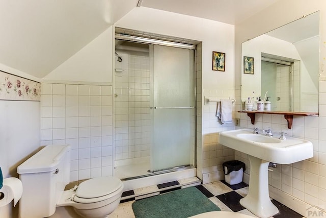 bathroom with tile patterned floors, a shower stall, toilet, and tile walls