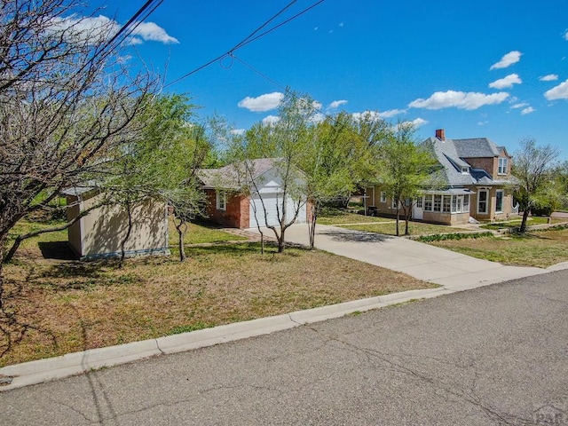 view of front facade featuring concrete driveway, a front yard, and a garage
