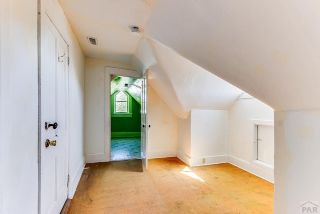 additional living space featuring baseboards, visible vents, and lofted ceiling