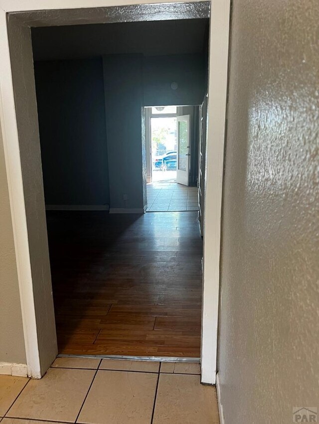 corridor with baseboards and tile patterned floors