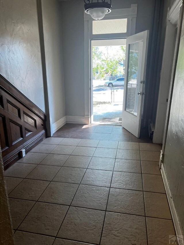 doorway to outside featuring tile patterned floors and baseboards