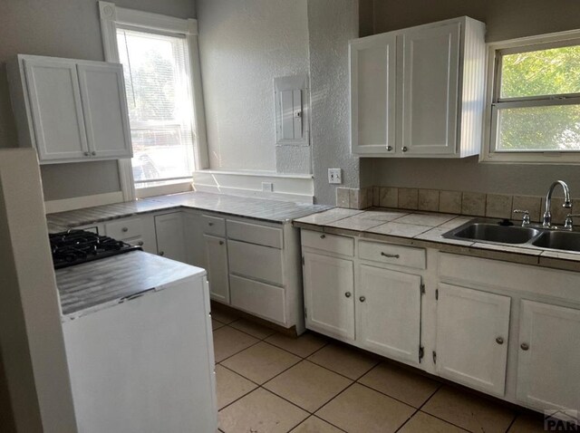 kitchen featuring plenty of natural light, tile counters, white cabinets, and a sink