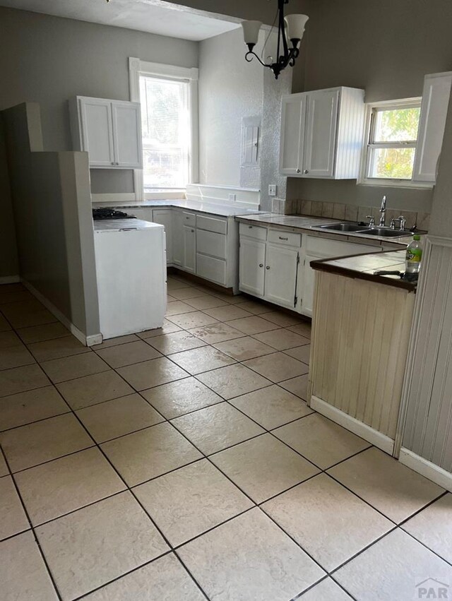 kitchen with plenty of natural light, white cabinetry, a sink, and light tile patterned floors