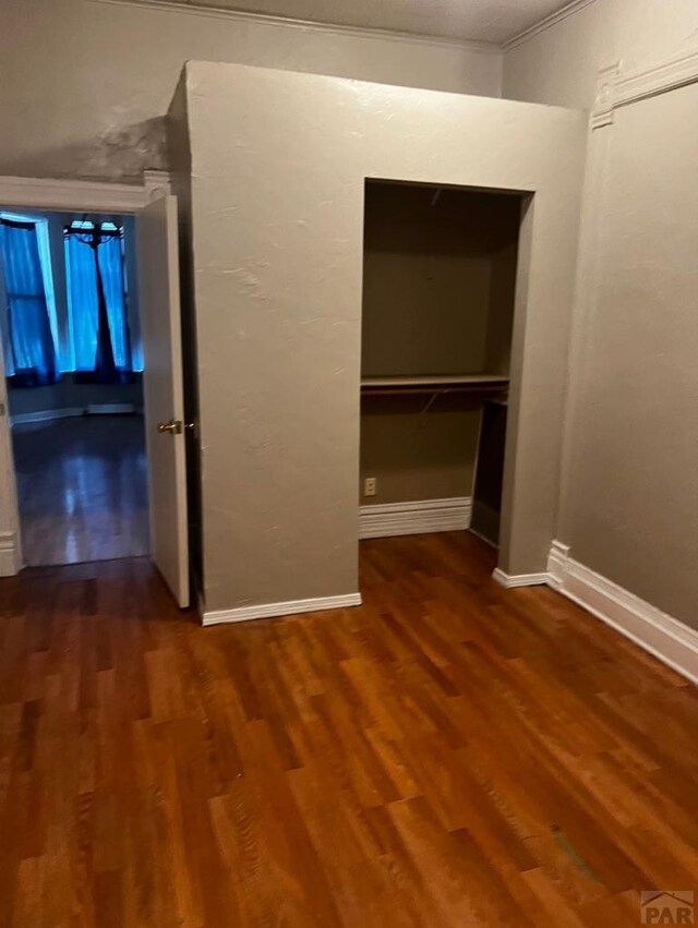 interior space featuring baseboards, dark wood finished floors, and crown molding