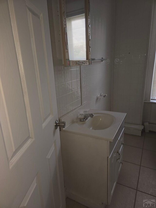 bathroom featuring a baseboard radiator, tile patterned flooring, vanity, and tile walls