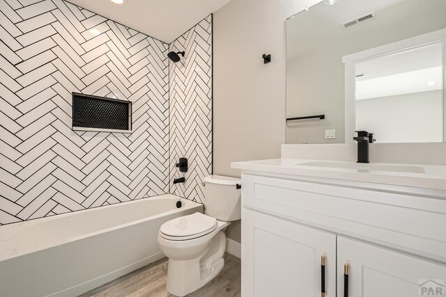 bathroom with visible vents, toilet, wood finished floors, bathtub / shower combination, and vanity