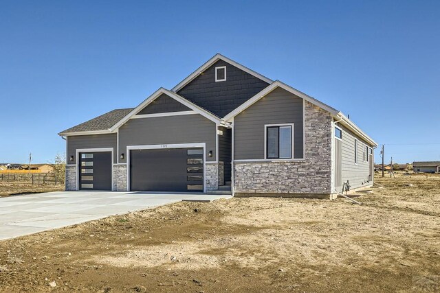 view of front of house featuring an attached garage, stone siding, and concrete driveway