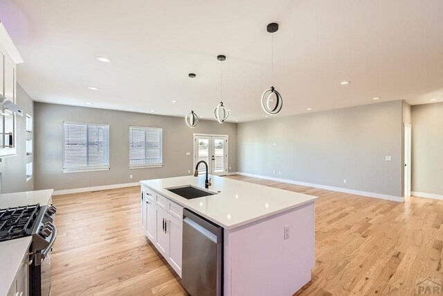 kitchen featuring a sink, white cabinetry, light countertops, stainless steel dishwasher, and an island with sink