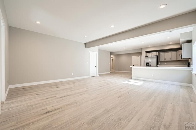 unfurnished living room with light wood finished floors, recessed lighting, and baseboards