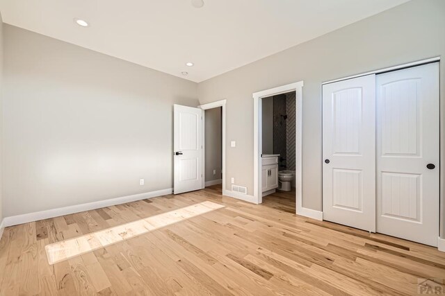 unfurnished bedroom with recessed lighting, visible vents, light wood-style flooring, ensuite bathroom, and baseboards