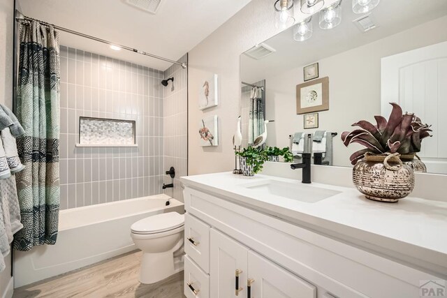 full bath with visible vents, toilet, shower / bath combo, vanity, and wood finished floors