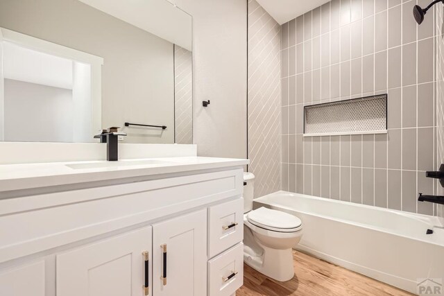 bathroom featuring toilet, vanity, wood finished floors, and bathing tub / shower combination