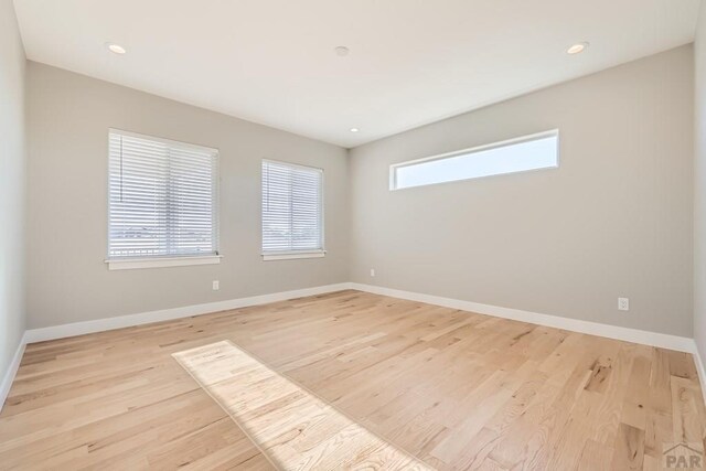 empty room with recessed lighting, light wood-style flooring, and baseboards