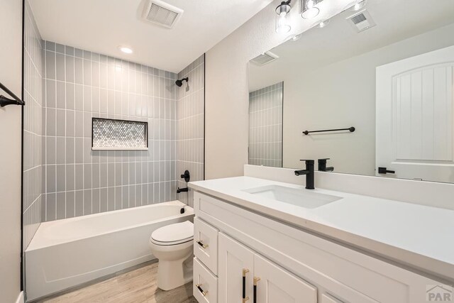 full bathroom with visible vents, bathing tub / shower combination, toilet, and wood finished floors