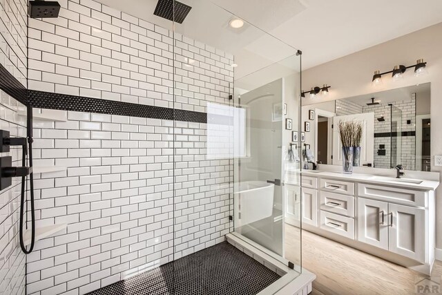 full bath with a sink, double vanity, and a shower stall