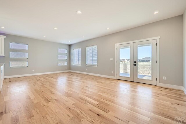 unfurnished living room with french doors, recessed lighting, light wood-style floors, and baseboards