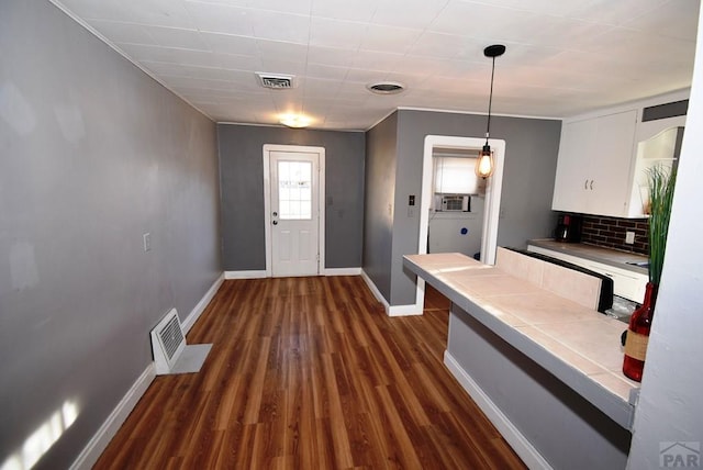 kitchen featuring tile counters, pendant lighting, white cabinets, and visible vents