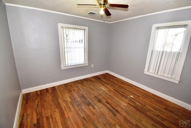 empty room with visible vents, baseboards, a ceiling fan, wood finished floors, and crown molding