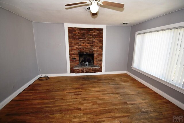 unfurnished living room featuring dark wood-type flooring, a fireplace, a ceiling fan, visible vents, and baseboards