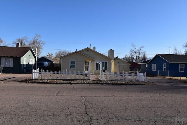 bungalow-style home with a fenced front yard, a residential view, and a chimney