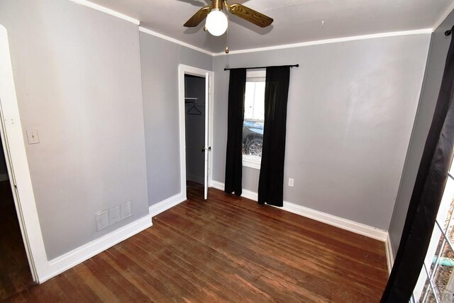 unfurnished bedroom with baseboards, visible vents, dark wood finished floors, a ceiling fan, and ornamental molding