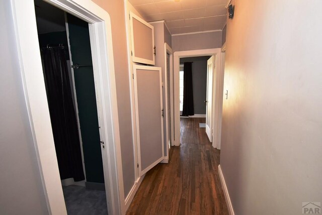 hall with dark wood-style flooring and baseboards