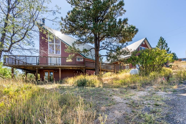 back of house featuring a chimney, metal roof, and a wooden deck