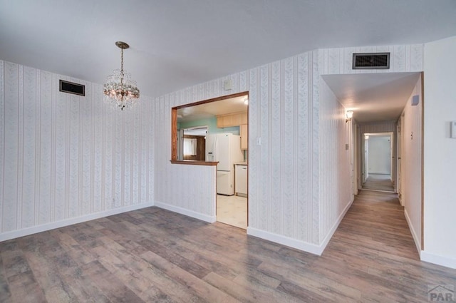 2621 Begonia St, Pueblo, CO 81005 - interior space featuring a notable chandelier, visible vents, wallpapered walls, and wood finished floors