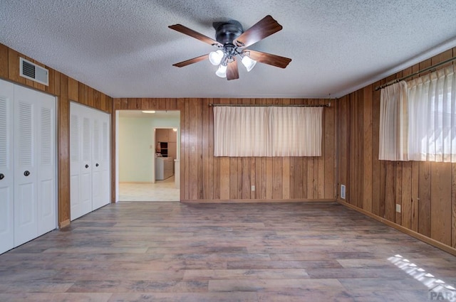 2621 Begonia St, Pueblo, CO 81005 - interior space featuring washer / clothes dryer, a ceiling fan, visible vents, wood finished floors, and wood walls