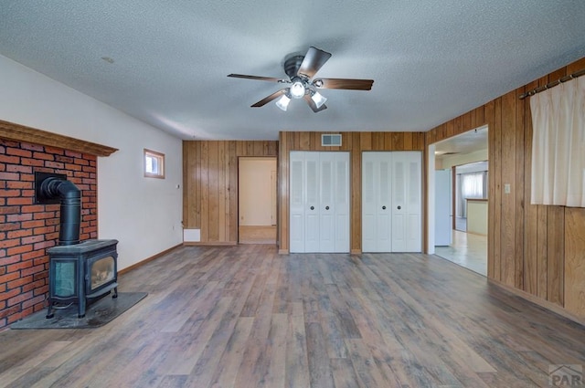 2621 Begonia St, Pueblo, CO 81005 - unfurnished living room with ceiling fan, a textured ceiling, visible vents, wood finished floors, and wood walls