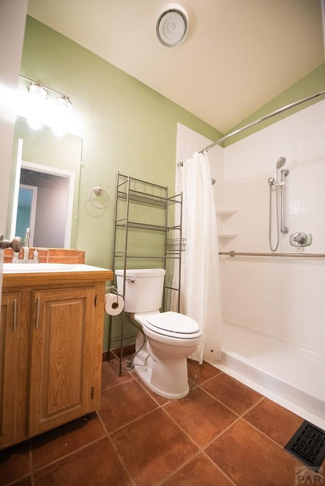 bathroom featuring tile patterned flooring, toilet, vanity, visible vents, and a tile shower