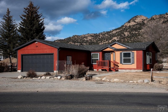 ranch-style home with a garage, a mountain view, and driveway