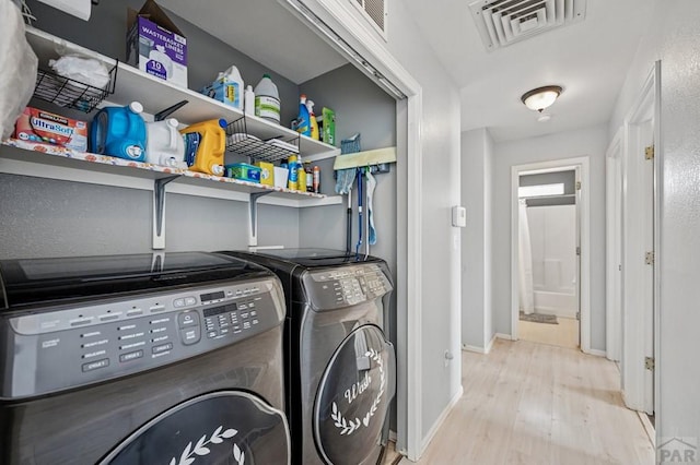 laundry room with visible vents, baseboards, laundry area, wood finished floors, and washer and dryer