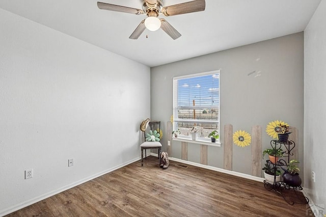 sitting room with a ceiling fan, visible vents, wood finished floors, and baseboards