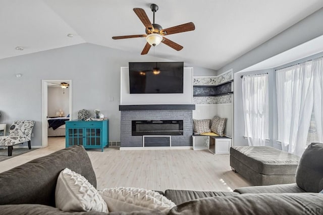 living room featuring vaulted ceiling, wood finished floors, a fireplace, and baseboards