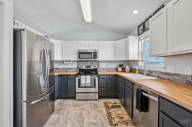 kitchen with gray cabinets, a sink, wood counters, appliances with stainless steel finishes, and vaulted ceiling