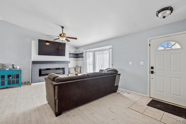 living room featuring light wood-style floors, a fireplace, visible vents, and lofted ceiling