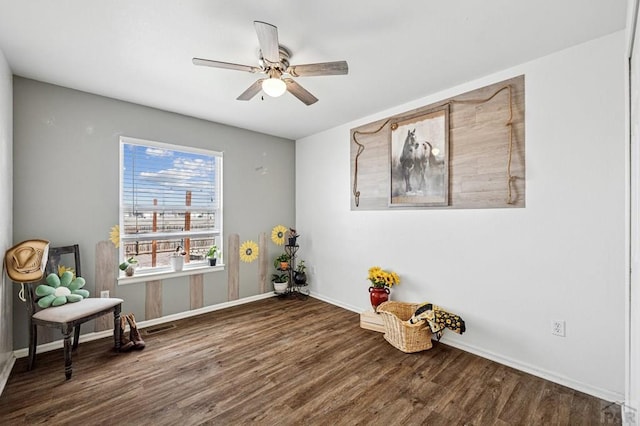 living area with visible vents, wood finished floors, baseboards, and ceiling fan