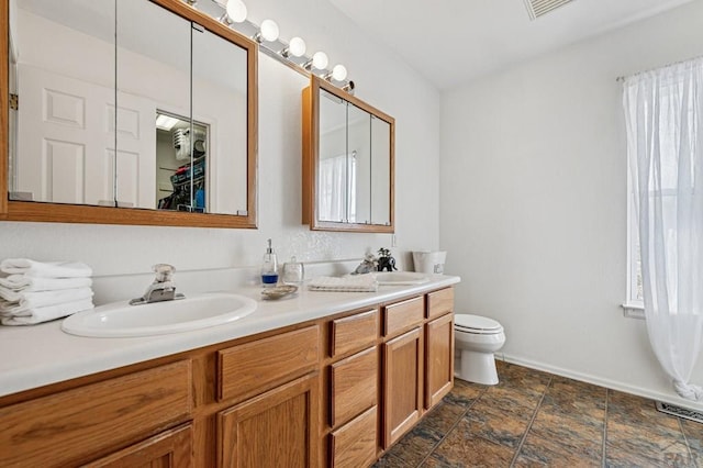 full bath featuring double vanity, visible vents, toilet, and a sink