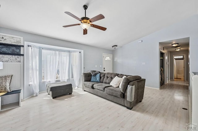 living room featuring lofted ceiling, light wood-style floors, baseboards, and ceiling fan