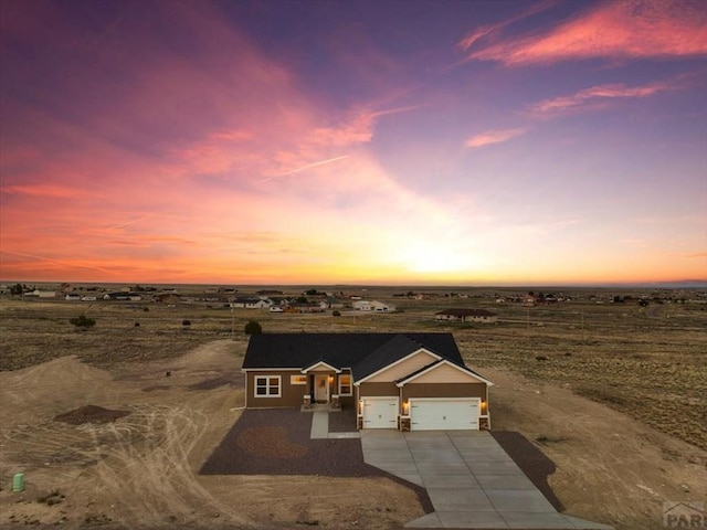 view of front of property with a garage, driveway, and a rural view